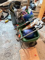 Overall lot showing Scotts spreader loaded with blue object, stacked plant pots, mulch bags and misc items