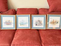 All four framed prints on couch, showing sizes, frames, mat colours