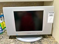 Front view of Sharp LC-13SH4U 13" LCD TV with stand and MaxSold lot tag
