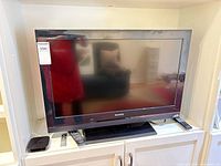 Front view of Sony 32-inch TV on stand with Apple TV box, Apple remote and Sony remote visible