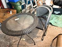 Full view of glass-top table with two wicker chairs