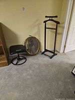 Mirror, stool and valet stand grouped against wall on carpeted floor