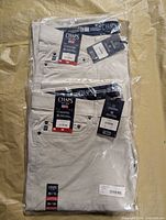 Two packaged pairs of Chaps stone pants, tags visible