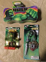 Overview of all three Hulk items: tin pencil case, mini jiggle head figure, jiggle head pen