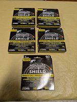 Front view of five sealed Mosquito Shield mosquito coil boxes