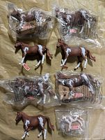 Group shot of 7 horses and 1 cow showing sealed and loose items