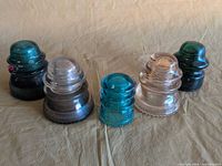 Group of five glass insulators showing colors and sizes