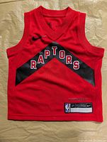 Front view of red Toronto Raptors toddler jersey displaying team name and Nike swoosh