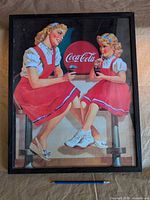 Front view of the framed Coca-Cola print with pencil for scale