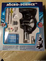 Front view of boxed Micro-Science 36-piece microscope set showing microscope and accessories