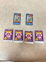 Six sealed trading card packs—four purple Score baseball, two blue Ultimate hockey—laid out on surface