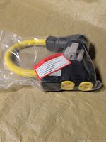 Full view of adapter in bag showing yellow cable and dual yellow outlets