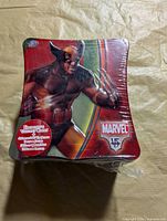 Top view of sealed hourglass-shaped tin with Wolverine artwork and label indicating variant card and booster packs