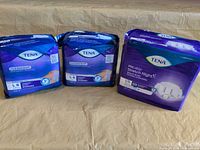 Three sealed TENA packs on surface