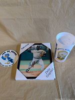 Group shot of all three items: framed photo, stadium cup, round sign