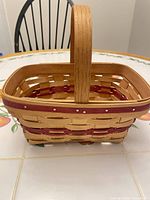 Side and top view of handwoven wooden basket showing red accent and handle