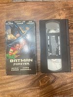 Front view of Batman Forever cardboard sleeve beside VHS cassette
