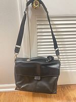 Front view of black laptop bag hanging by shoulder strap