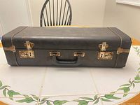 Closed black rectangular instrument case on table showing exterior, handle, and latches