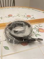 Coiled black studded belt inside plastic bag