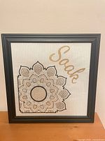 Full view of framed cross-stitch wall art with mandala and "Soak" text