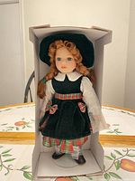 Full view of doll in box showing outfit and stand