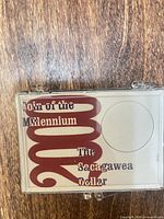 front view of closed clear acrylic coin case showing insert text and coin aperture