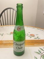 Full view of green Clicquot Club bottle on table