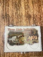 Front view of closed acrylic display case showing Three Little Indians insert and three coin wells