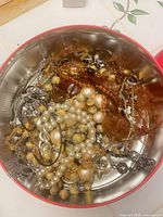 Overview of assorted jewelry inside metal tin