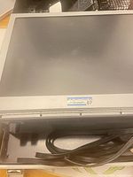 Front of projector showing hinged screen with Fairchild 07 logo and power cord stored in base