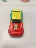 Top and front view showing red hood with Robin R logo, yellow roof, green sides