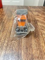 Front view of sealed orange die-cast van in plastic bag