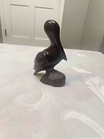 Left side view of carved wooden pelican on base