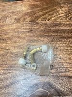 Door stop sealed in plastic showing brass arm and white bumpers