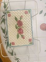 Top view of floral basket-weave stoneware trivet seated in metal stand