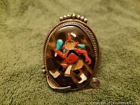 Front view of the Native American sterling silver bracelet showing the stone inlay Kachina dancer design with missing pieces on the main stone.