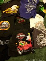 Overview of multiple Harley Davidson apparel items laid out showing various logos, graphics, and colors including black, white, blue, and multicolor elements.