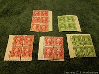 Photo showing multiple blocks of unused vintage US stamps in red and green colors, with perforations and margin markings.