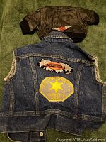 Back side of brown leather jacket with ribbed cuffs and small Harley-Davidson patch, and back of denim vest with Harley-Davidson patch and Dillon County Sheriff's Dept. star patch