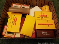 Box of assorted 35mm slide storage boxes, mostly yellow Kodaslide branded, some white and brown, and Nimrod box visible.