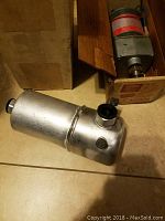 Two mechanical parts shown: a cylindrical Dayton motor in a box and a silver Delco automotive fluid part outside another box.