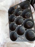 Top view of vintage cast iron muffin pan showing 12 muffin cups with some wear.