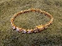 Photo of sterling silver bracelet with blue stones laid flat showing entire length and clasp.