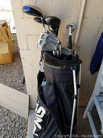 Full view of golf bag filled with Ping Eye 2 irons and other golf clubs including drivers and wedges