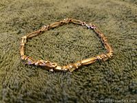 Full view of the sterling silver bracelet laid flat showing the linked oval design and missing a stone.