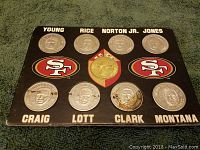 Photo of the coin set mounted on a black card with nine silver coins showing player portraits and names with some discoloration or dark marks on bottom coins.