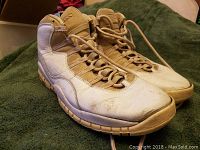 Photo of Nike Air Jordan sneakers showing side view with laces tied and visible dirt and wear on white leather and tan outsole.