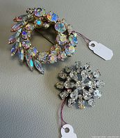 Both brooches together showing design and size tags