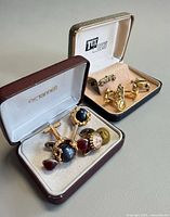 Overall view of both presentation cases showing tie bar, car cufflinks and assorted cufflinks